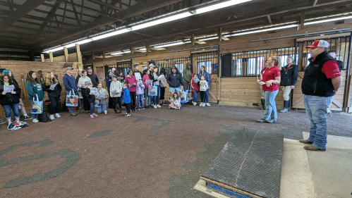 A graduate student speaking to a group of students in a barn.