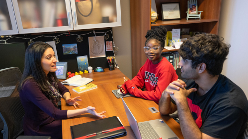 An advisor speaking to two students in an office.